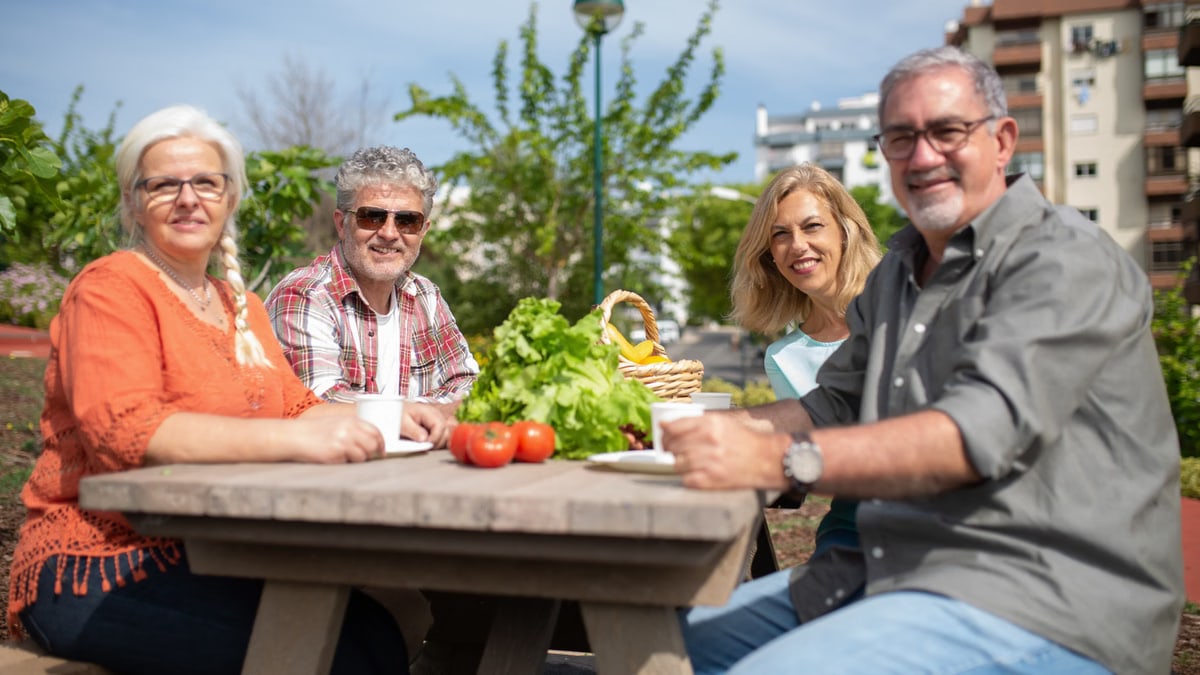 Happy group of seniors enjoying a picnic outdoors with fresh vegetables.