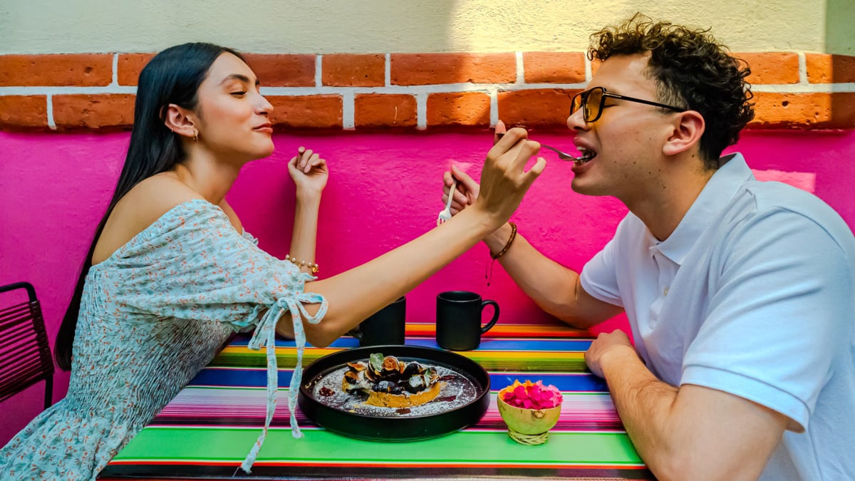 A joyful couple shares a dessert at a colorful café in Mexico City, CDMX.